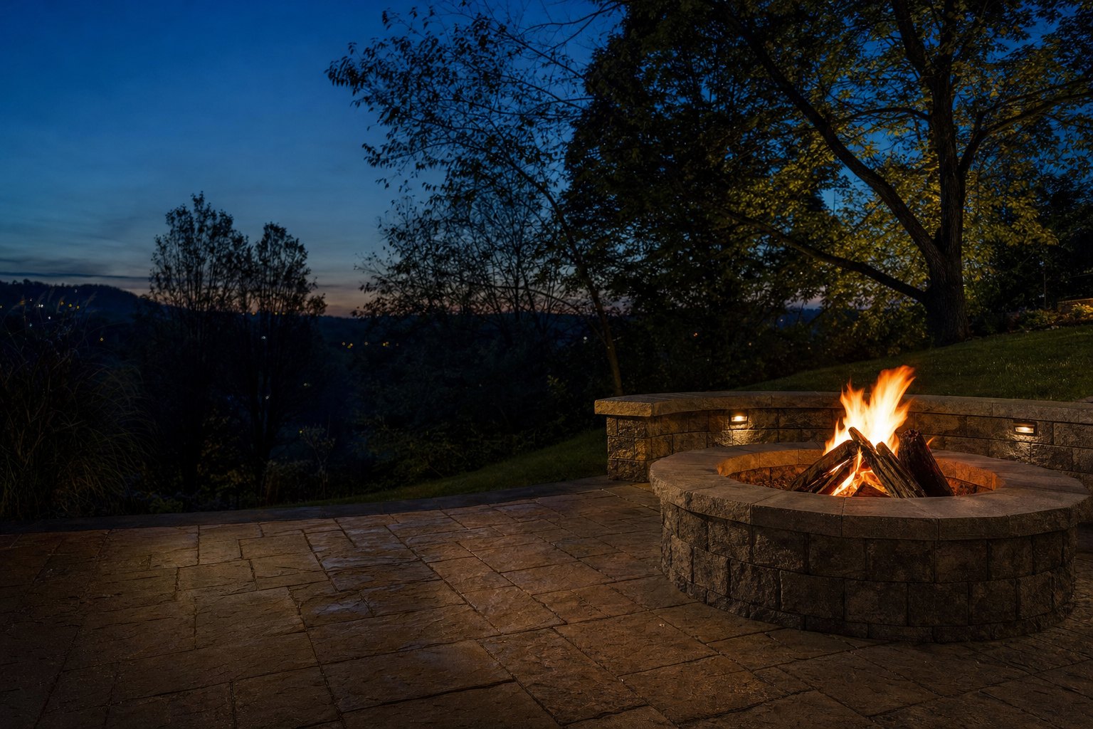 Wood-burning block fire pit on a paver patio at blue hour